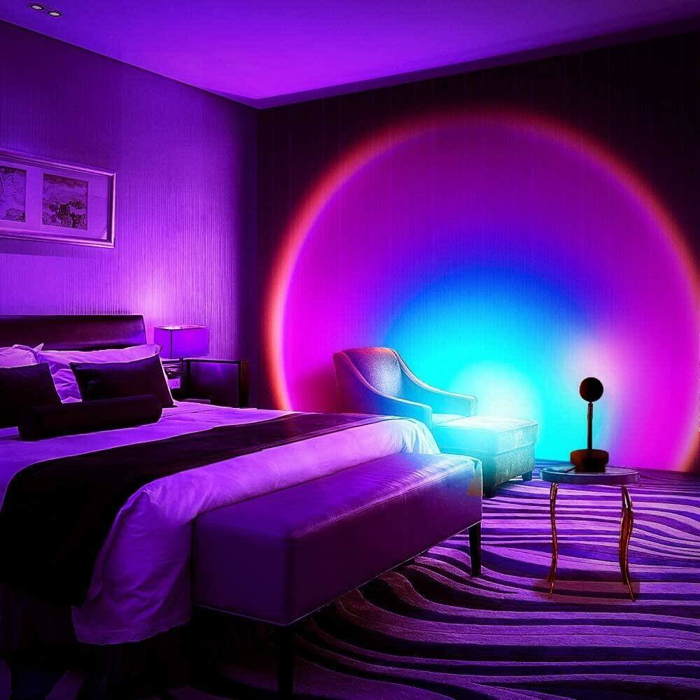 Bedroom illuminated by a sunset lamp casting a vibrant blue, purple, and red gradient on the wall, creating a relaxing and aesthetic nighttime atmosphere.