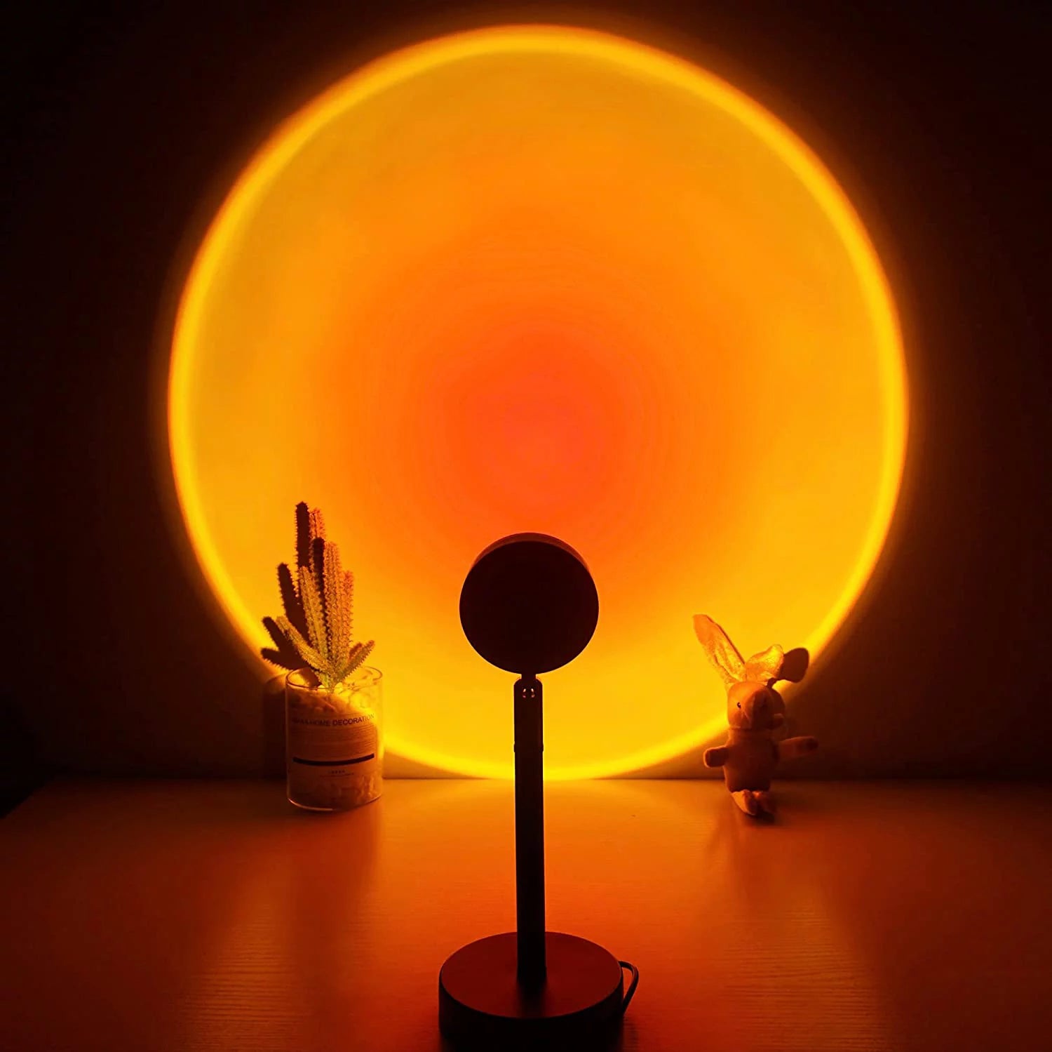 Sunset lamp projecting a vivid circular orange glow on the wall, creating a warm and calming atmosphere in a dark room with minimal decor.