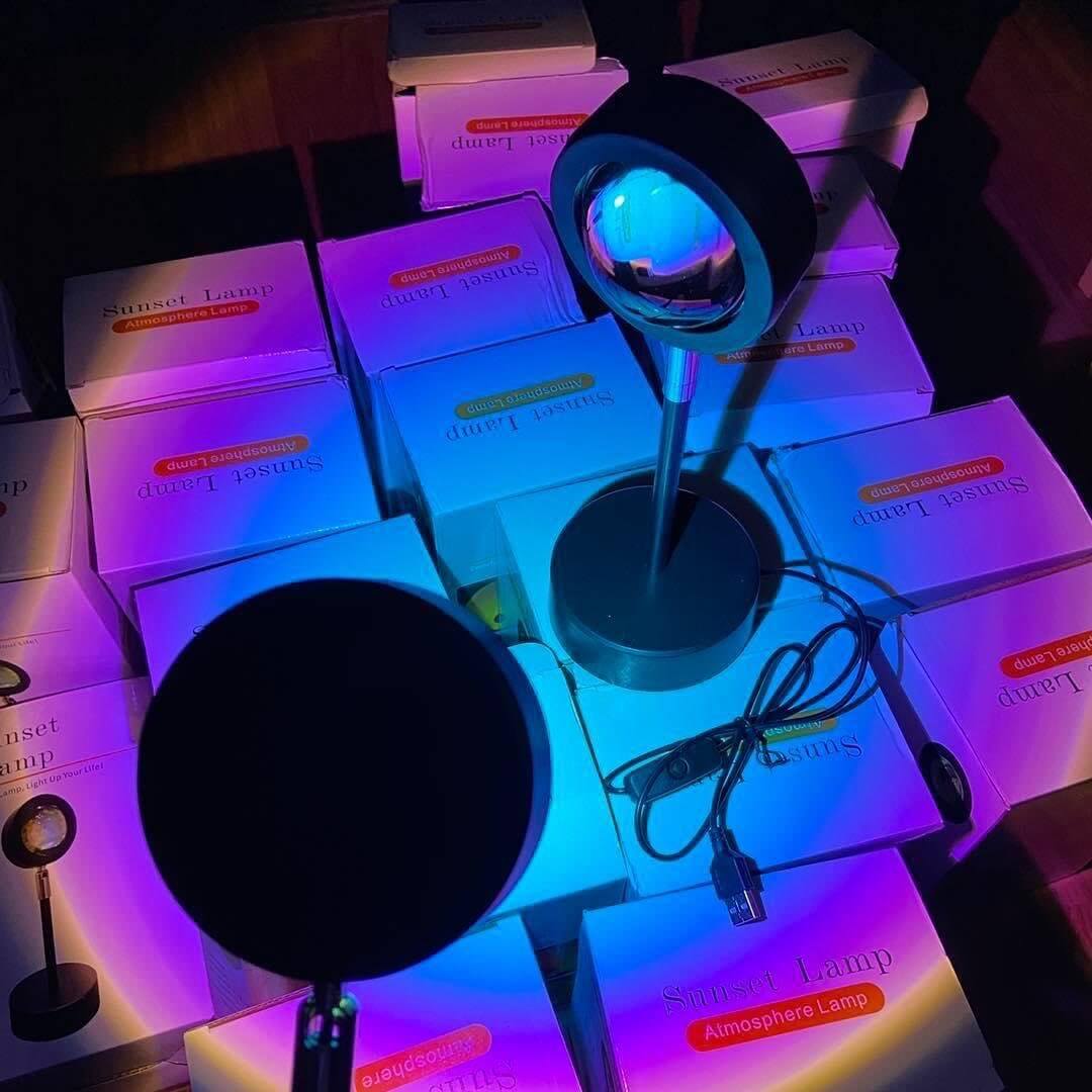 Multiple sunset lamps projecting overlapping purple, pink, and blue gradients onto a tiled surface, creating a vibrant ambient lighting display.
