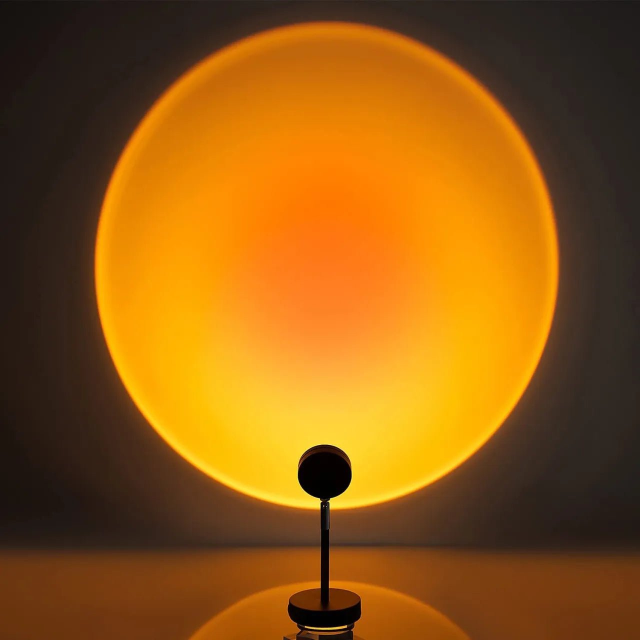 Minimalist sunset lamp projecting a warm orange and red gradient circle on a wall, creating a soft and calming atmosphere in a dark room