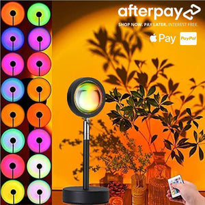 Multicolor sunset lamp with 16 adjustable color modes, remote control, and floral decor, casting a warm glow on an orange-toned wall.